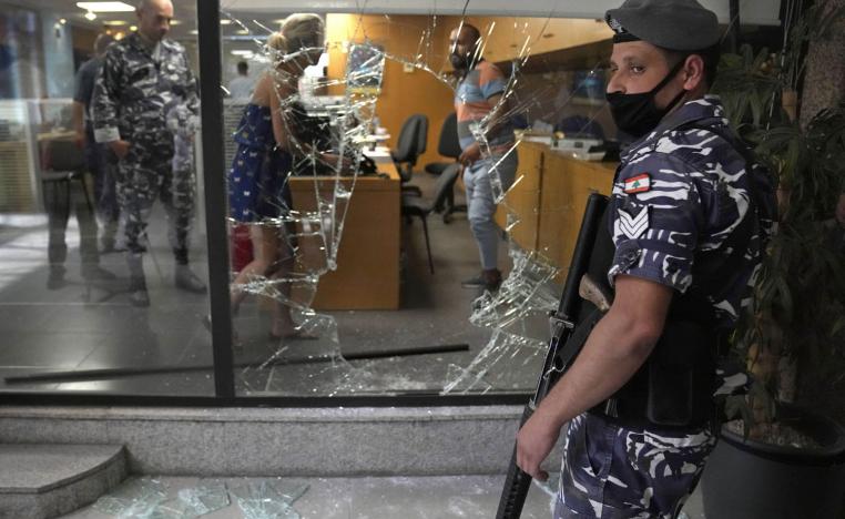 شرطي لبناني يحرس ثغرة في الواجهة الزجاجية لمصرف في بيروت