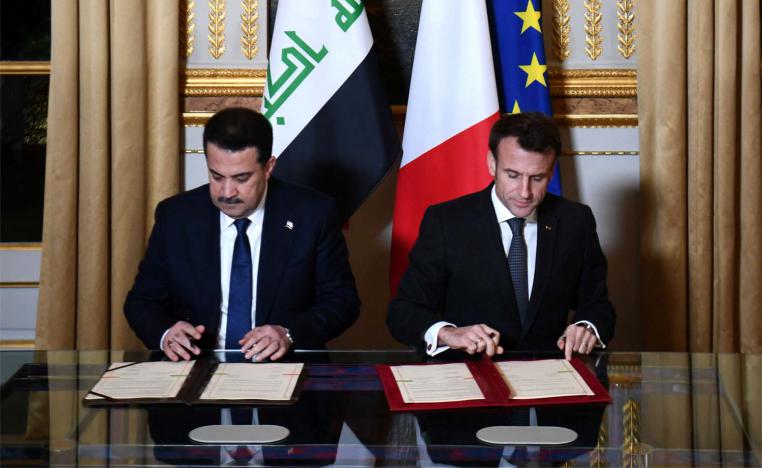 French President Emmanuel Macron and Iraq's Prime Minister Mohammed al-Sudani sign documents at the Elysee Presidential Palace