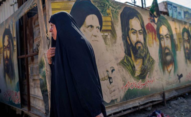 عراقية تمر بجانب جداريات لصور أئمة شيعة في مدينة الصدر ببغداد