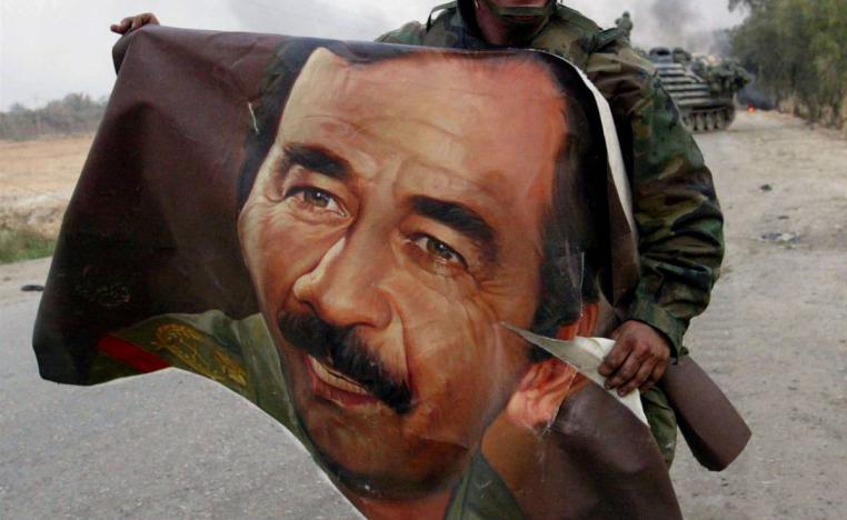جندي أميركي يحمل صورة للرئيس العراقي الراحل صدام حسين بالقرب من جسر على دجلة جنوب بغداد (2003)