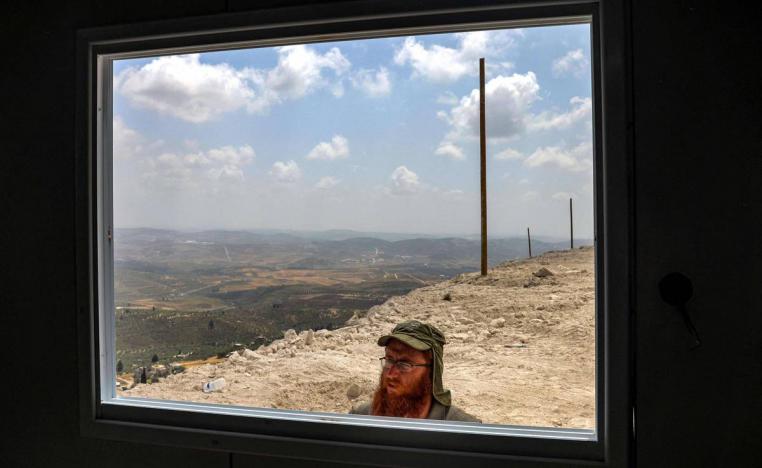 إسرائيلي يطل على مبنى في مستعمرة في الضفة