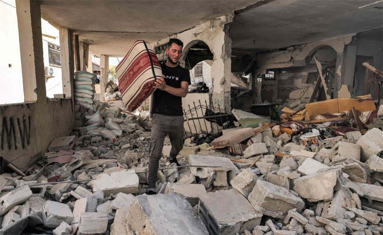 A man walks with a cushion through rubble in a destroyed flat in a building in Jenin