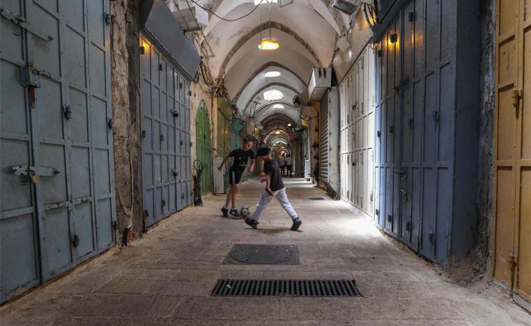 Youths play football near shuttered shops during a Palestinian general strike in Jerusalems old city