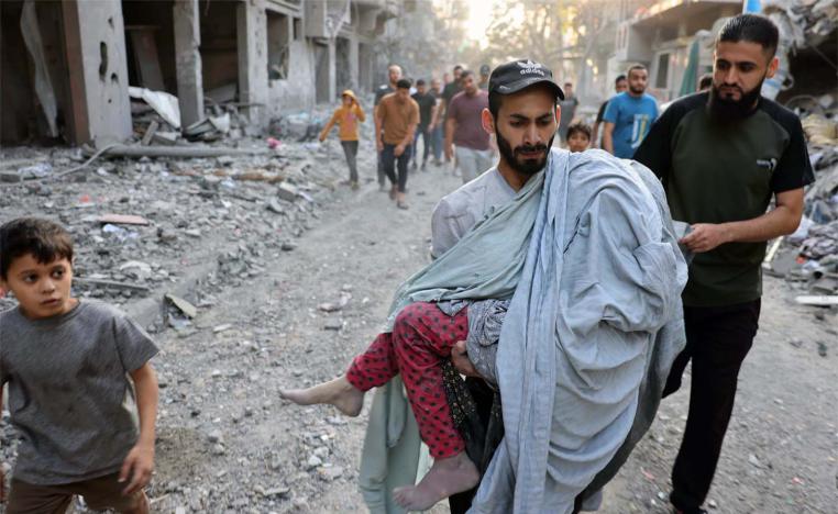 A Palestinian man carries the covered body of a girl removed from the rubble of a building in central Gaza