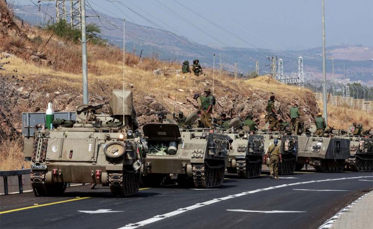 A convoy of Israeli Armoured Personnel Carriers drives on a road near Israel's border with Lebanon