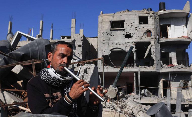 فلسطيني يعزف الناي بجوار اطلال مبان مدمرة بالقصف الإسرائيلي