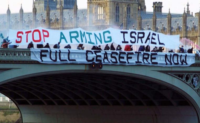 Pro-Palestinian activists unflur banners calling on the British government to demand a full ceasefire in Gaza