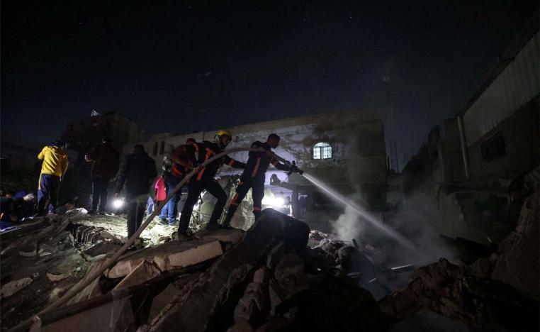 Firefighters spray water on the rubble of a building following Israeli bombardment in Rafah