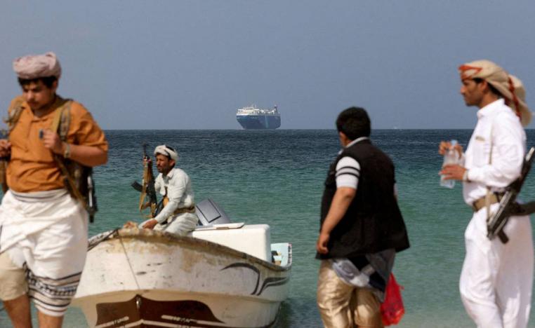 مسلحون حوثيون ينظرون إلى سفينة شحن تم ايقافها في البحر الأحمر