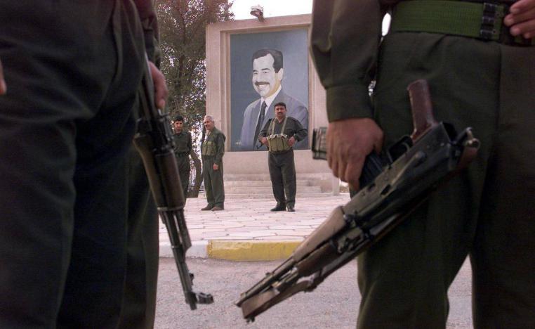 مسلحون عراقيون أمام صورة للرئيس العراقي صدام حسين في بغداد (مارس 2003)