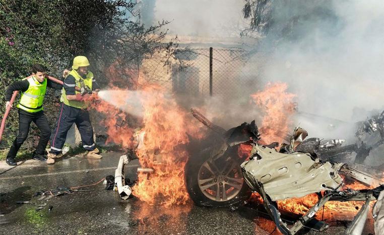Firefighters douse a burning car after it was hit in the Israeli drone attack