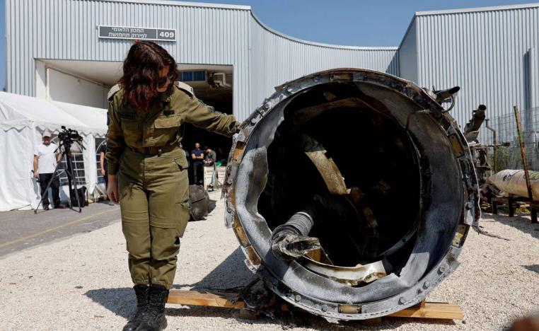 مجندة إسرائيلية تتفحص بقايا صاروخ إيراني