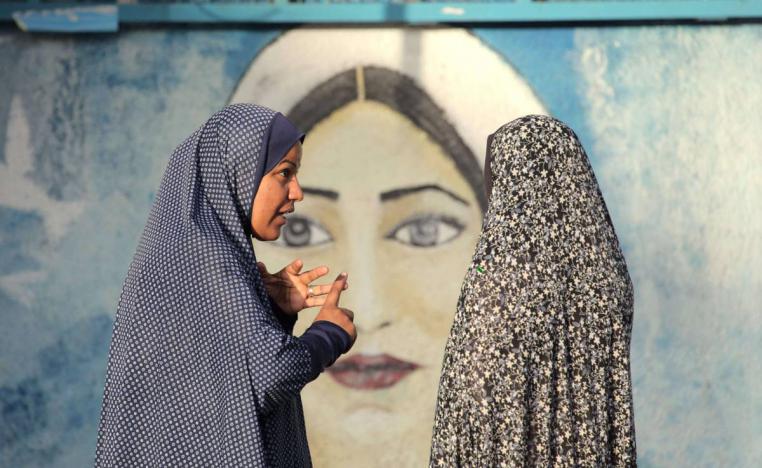 فلسطينيات أمام جدارية للمرأة الفلسطينية في غزة