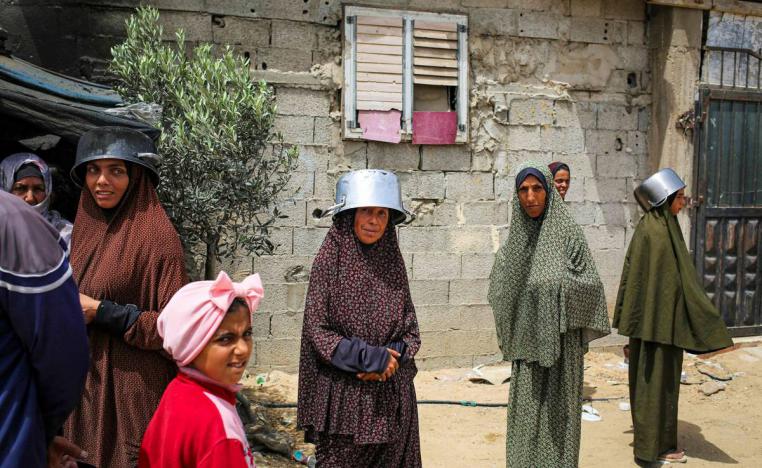 فلسطينيات ينتظرن تسليم وجبات المساعدات في رفح
