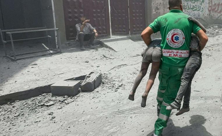 مسعف فلسطيني يحمل طفلين فلسطينيين من موقع قصف إسرائيلي لغزة