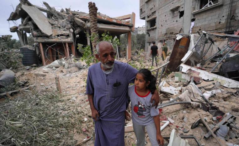 فلسطينيون عند ركام مبان دمرها القصف في غزة