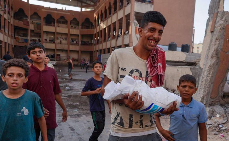 فلسطيني يحمل كيس طحين من الاسقاطات الجوية على خان يونس في غزة