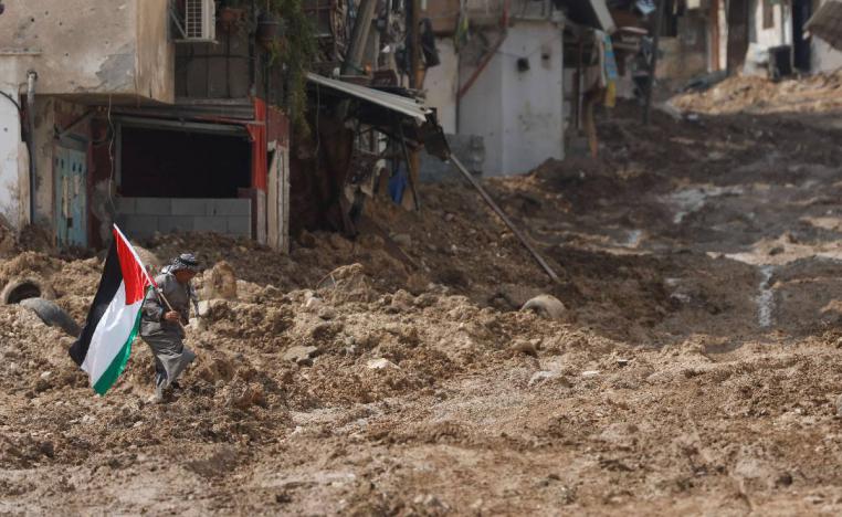 فلسطيني يرفع علما في شارع مدمر في طولكرم