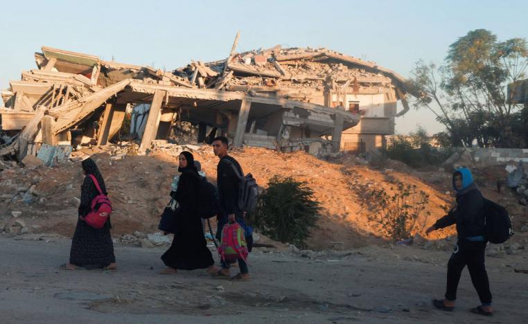 أسرة فلسطينية أمام مبان مدمرة في خان يونس بغزة