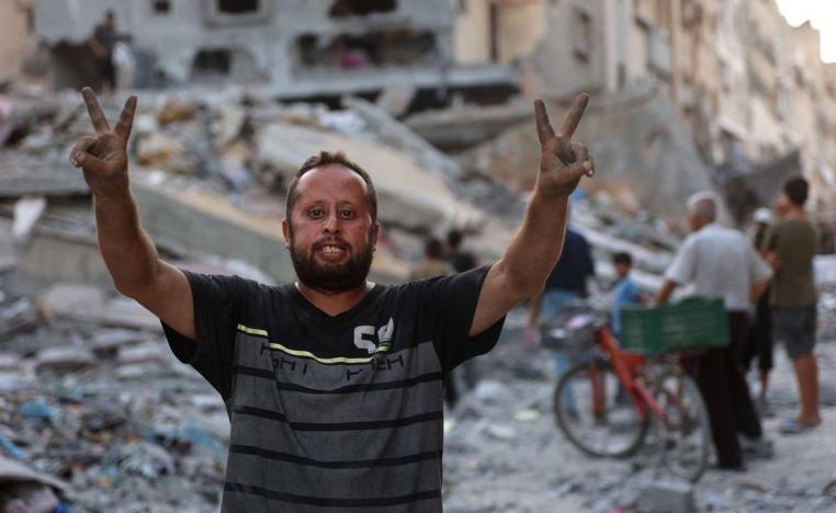 فلسطيني يرفع علامة النصر أمام مبنى مدمر في غزة