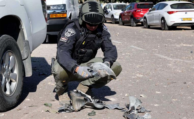 An Israeli policeman gathers debris at the site of a rocket attack, fired from Lebanon, in Kibbutz of Maagan Michael