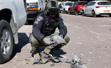 An Israeli policeman gathers debris at the site of a rocket attack, fired from Lebanon, in Kibbutz of Maagan Michael