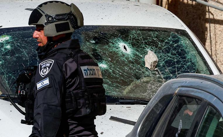 An Israeli security forces member stands next to a damaged car at the site of a drone attack