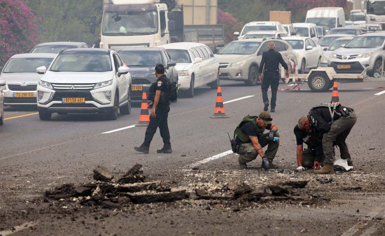 Members of Israeli security forces inspect the impact site of a reported rocket fired from Lebanon on central Israel