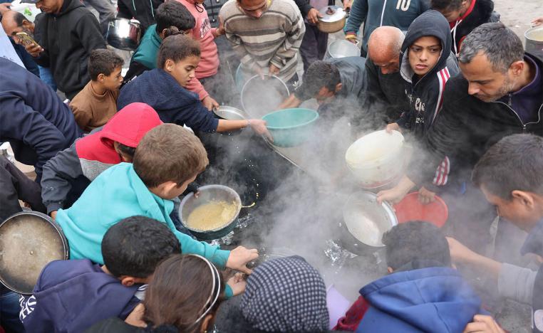 alestinians queue to receive a food ration outside a distribution center west of Gaza City