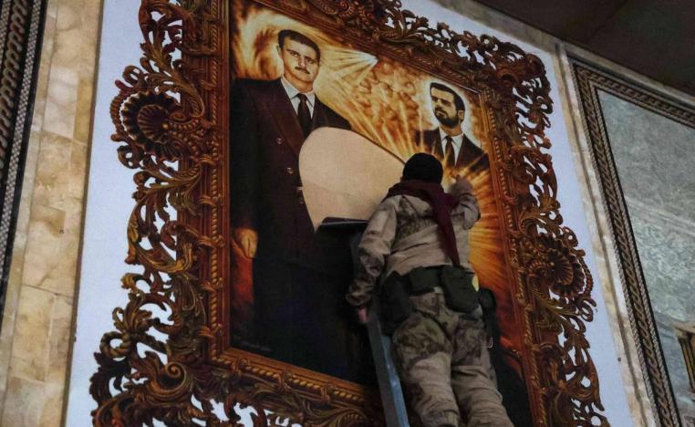 مقاتلو المعارضة يمزقون لوحة للرئيس بشار الأسد وأخيه الراحل باسل في مطار حلب
