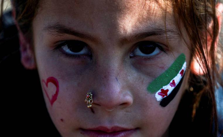 فتاة سورية تضع علم سوريا الجديد/القديم على وجنتها