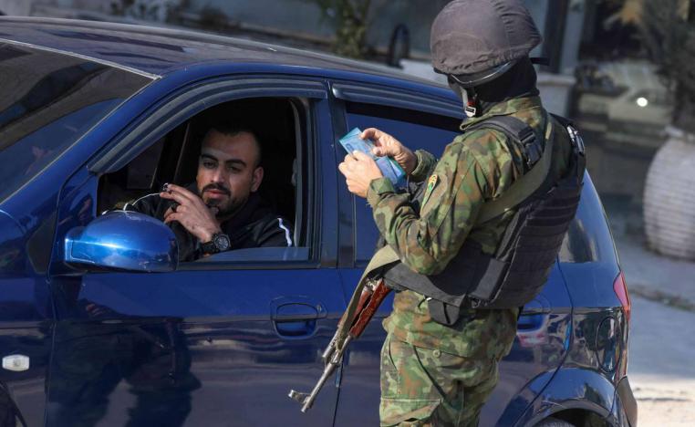شرطي فلسطيني يدقق هوية شخص عند مدخل مخيم جنين