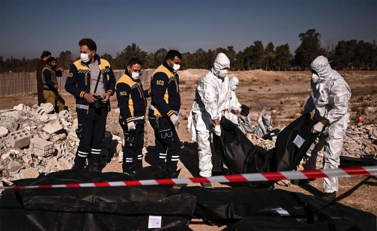 Members of Syria's White Helmets civil defence transport body-bags containing human remains that were recovered from a mass grave in Damascus