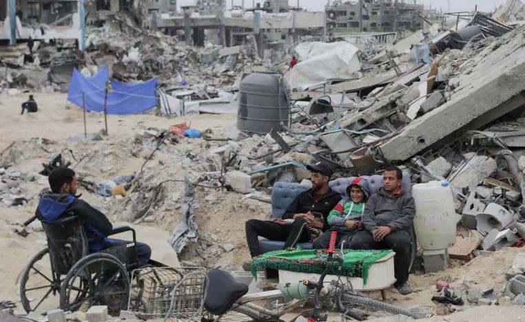 فلسطينيون يجلسون أمام انقاض منازلهم في غزة