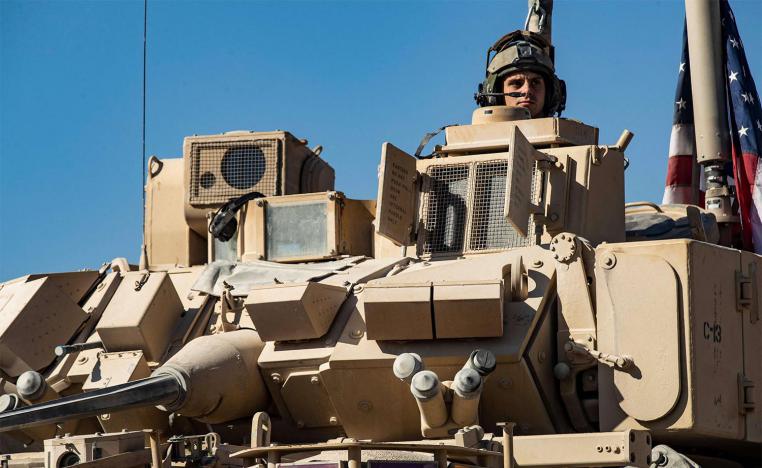 A US soldier monitors the area as troops patrol oil fields near Syria's northeastern border with Turkey