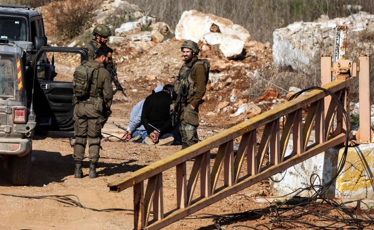 Israeli soldiers stand near Lebanese detainees at the Israeli-Lebanese border