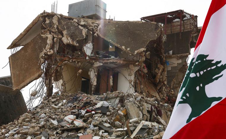 ebanon's flag next to a damaged building in the southern Lebanese village of Kfar Kila