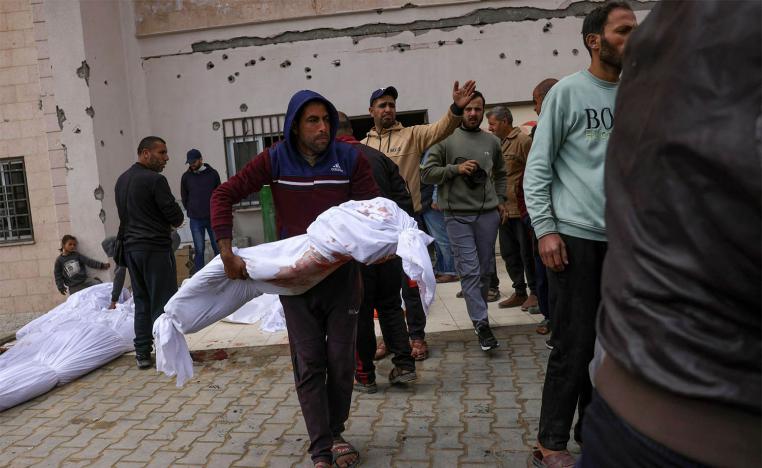 A Palestinian man carries the body of a young victim killed in Israeli overnight airstrikes in the northern Gaza Strip