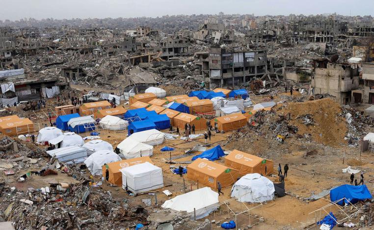 Palestinians walk around their tents, set up amid heavily damaged buildings in Jabalia