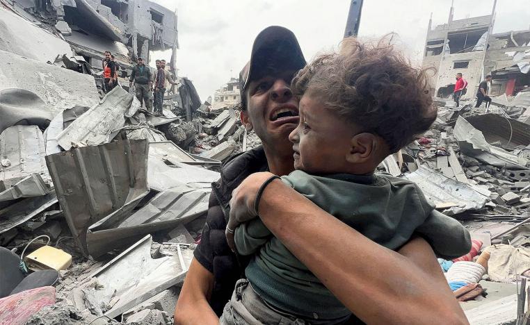 A Palestinian man cries as he holds a child at the site of an Israeli strike on a house in Shejaia in Gaza City