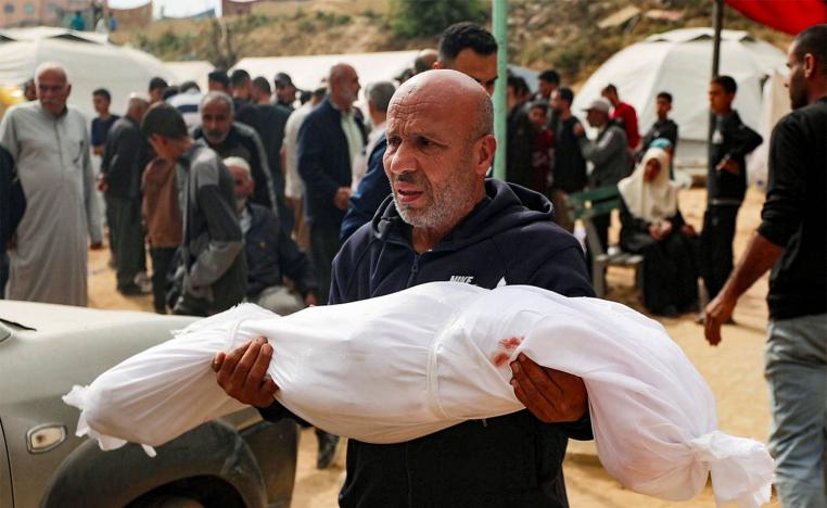 A man reacts holding the body of a Palestinian child killed in Israeli strikes on Gaza
