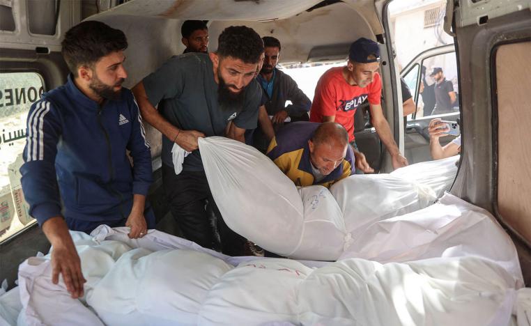 People unload the shrouded bodies of people killed in an Israeli strike, at Al-Shifa hospital in Gaza City 