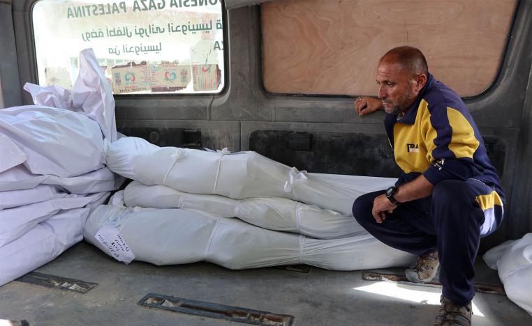A man sits next to the shrouded bodies of people killed in the Israeli strike on the school