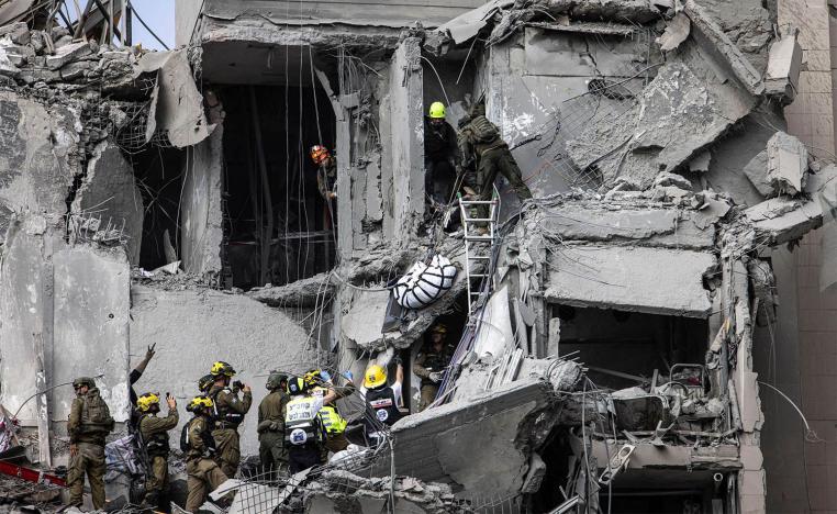 Israeli emergency services and security officers evacuate a body from the rubble of a building hit by an Iranian missile in Beersheba in southern Israel 