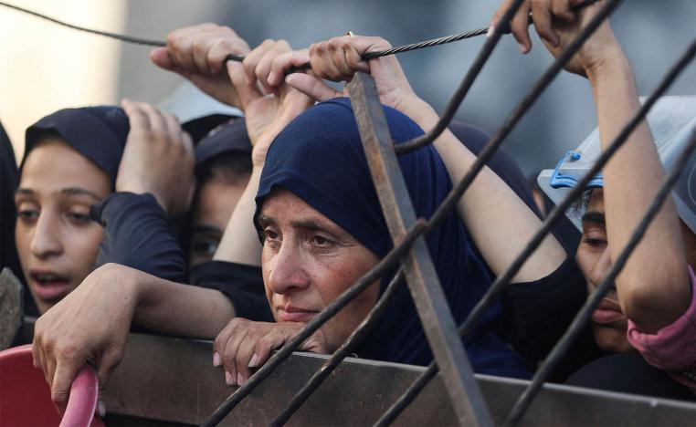 Palestinians look on as they wait to receive food from a charity kitchen amid a hunger crisis in Gaza City