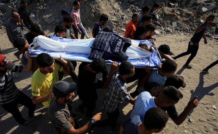 People carry the body of a Palestinian journalist, Adam Abu Harbid, killed in an overnight Israeli airstrike