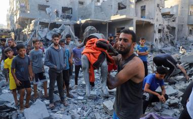 A man carries the body of Palestinian girl Amal Zakot, who was killed in an Israeli strike on a house in Gaza City