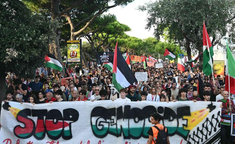 People march behind a banner reading Stop Genocide as part of a demonstration in support of Gaza and Palestinian people at Venice Lido