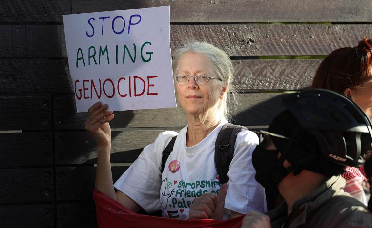 A demonstrator holds a placard reading "Stop Arming Genocide" in a protest outside the entrance to the Defence and Security Equipment International fair at the ExCeL centre in east London