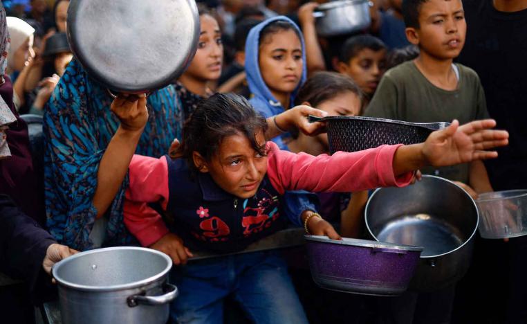Palestinians gather to receive food from a charity kitchen, in Nuseirat, central Gaza Strip, October 7, 2025. 